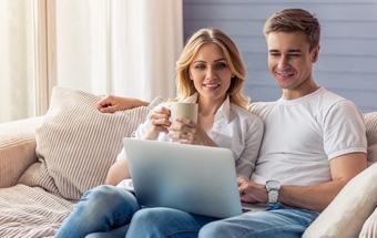 A young couple using laptop sitting on a sofa