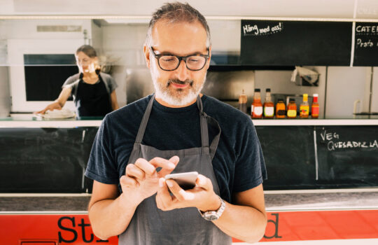 A man using his phone in a food van.