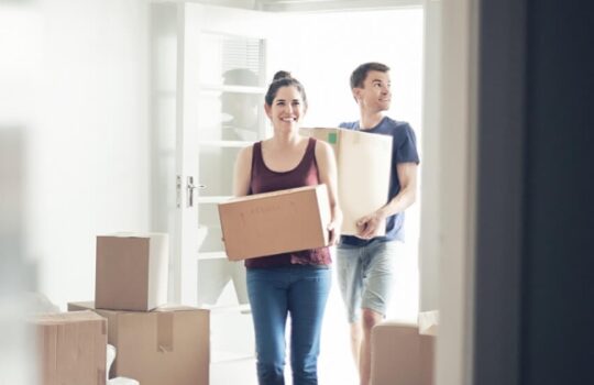 A happy couple moving boxes into a new house